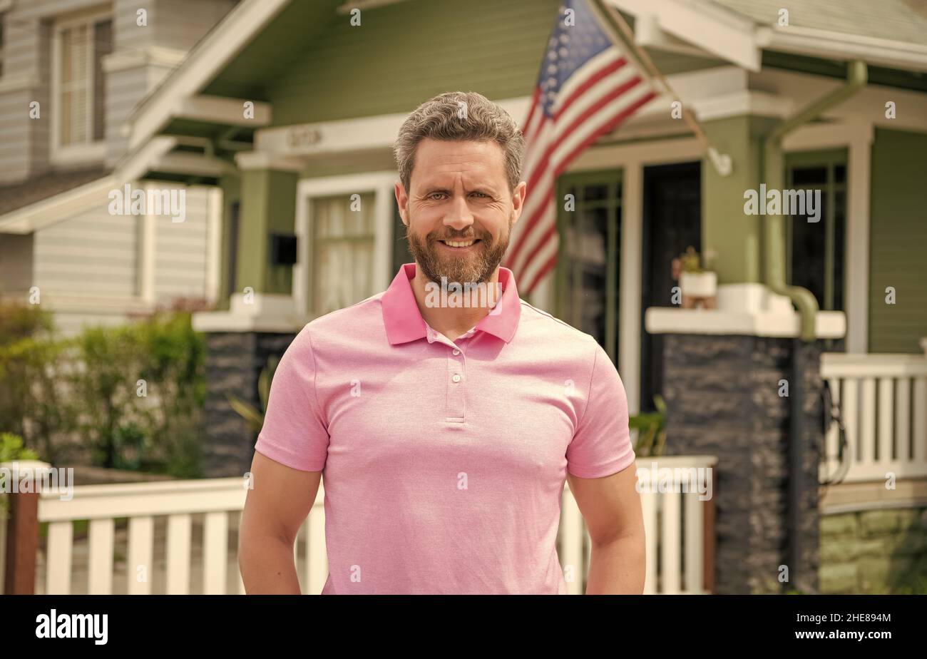 happy bearded man realtor selling or renting house with american flag, real estate Stock Photo