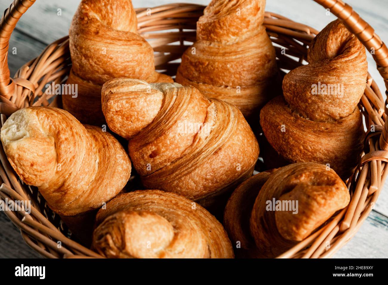 Croissants in a wicker basket on a wooden background. Closeup. Stock Photo