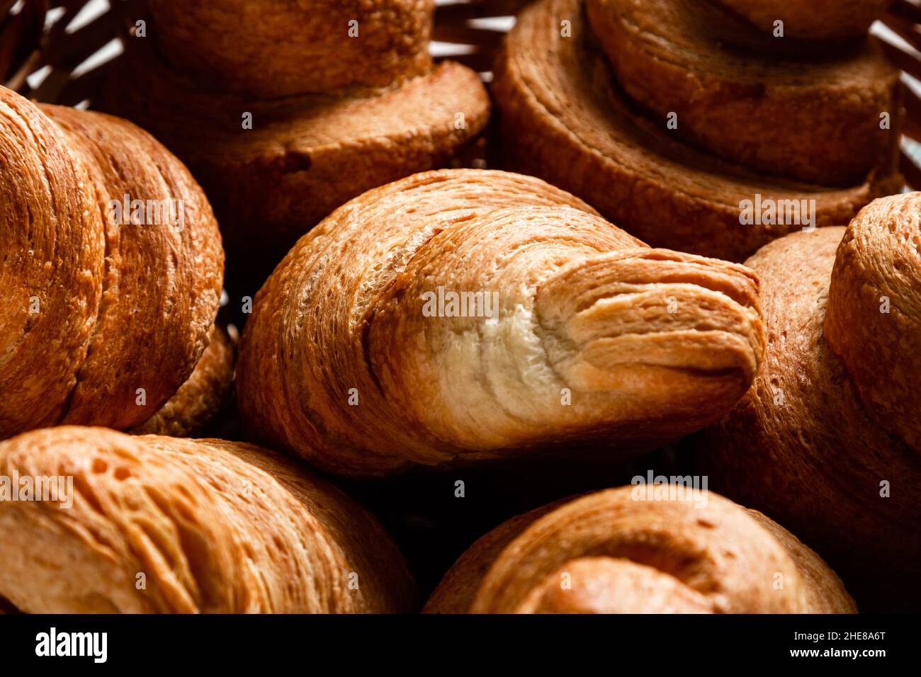 Croissants in a wicker basket on a wooden background. Close-up. Stock Photo