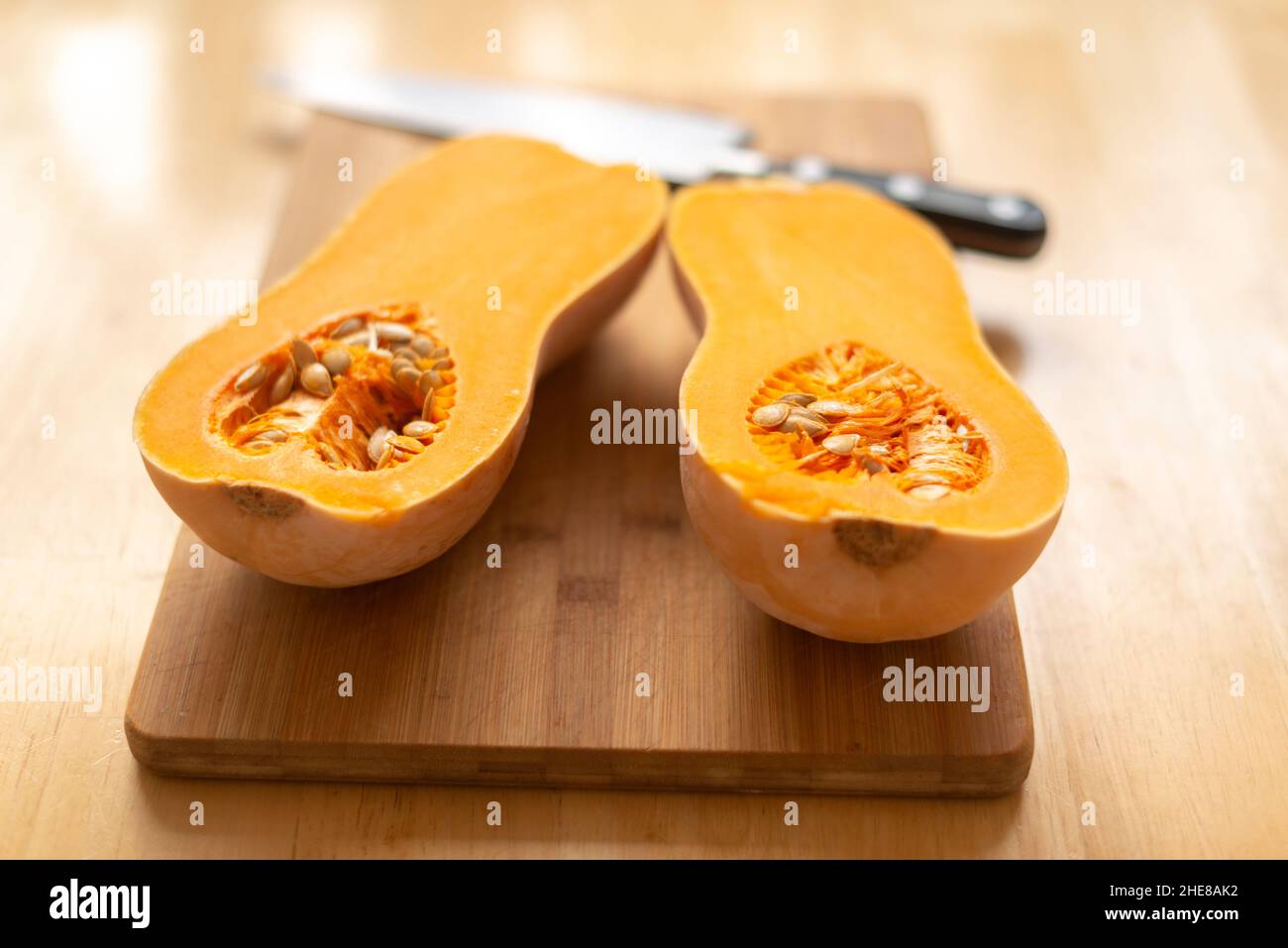 Butternut squash (Cucurbita moschata)-mcut in half on a chopping board-selective focus Stock Photo