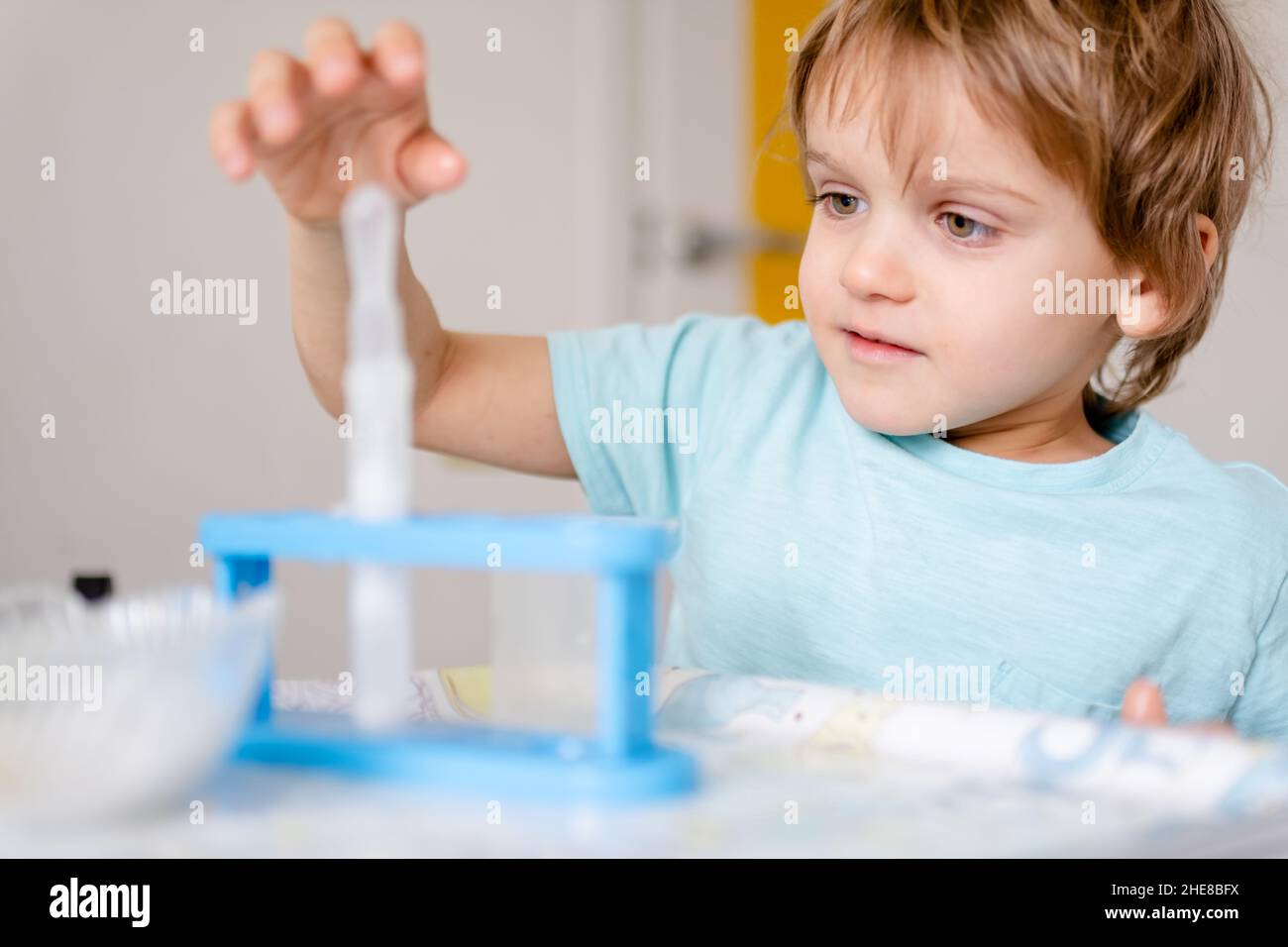 Happy boy in blue Tshirt conducts chemical experiments with vinegar