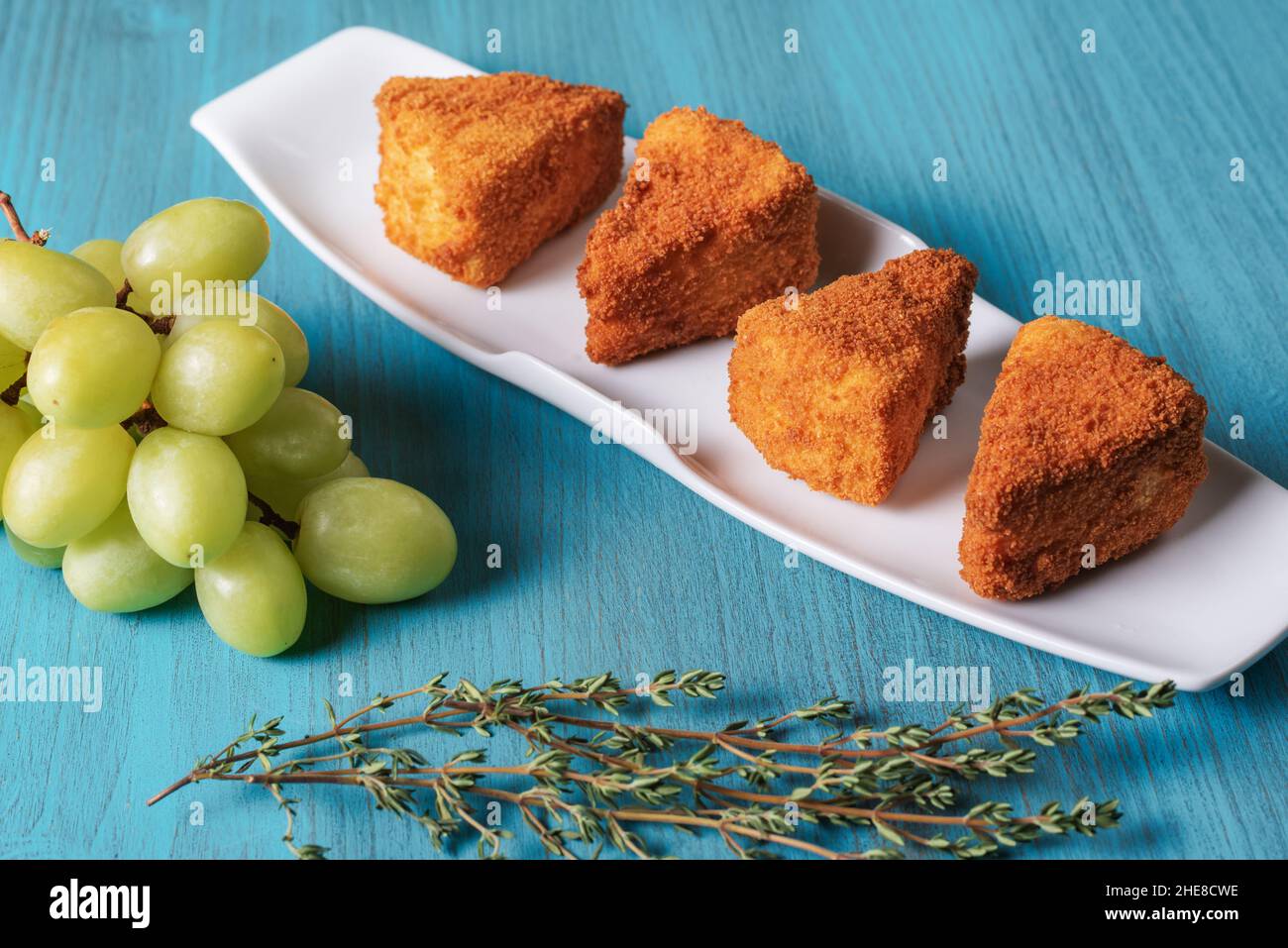 Camembert cheese fried in portions and presented with a bunch of grapes