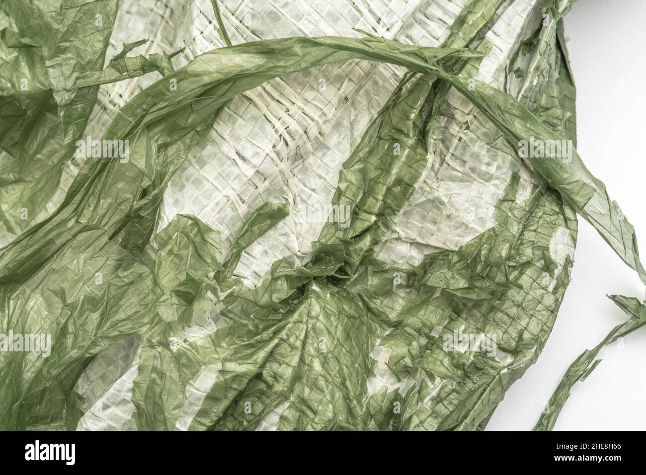 Close-up of very worn green cheap Poly-Tarpaulin - exposed inner woven plastic fabric laminated with green LDPE / Low-density Polyethylene. Stock Photo