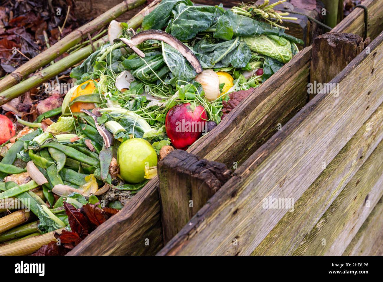 Pile of fruit and vegetable scraps in homemade wooden compost bin in the garden, selective focus Stock Photo