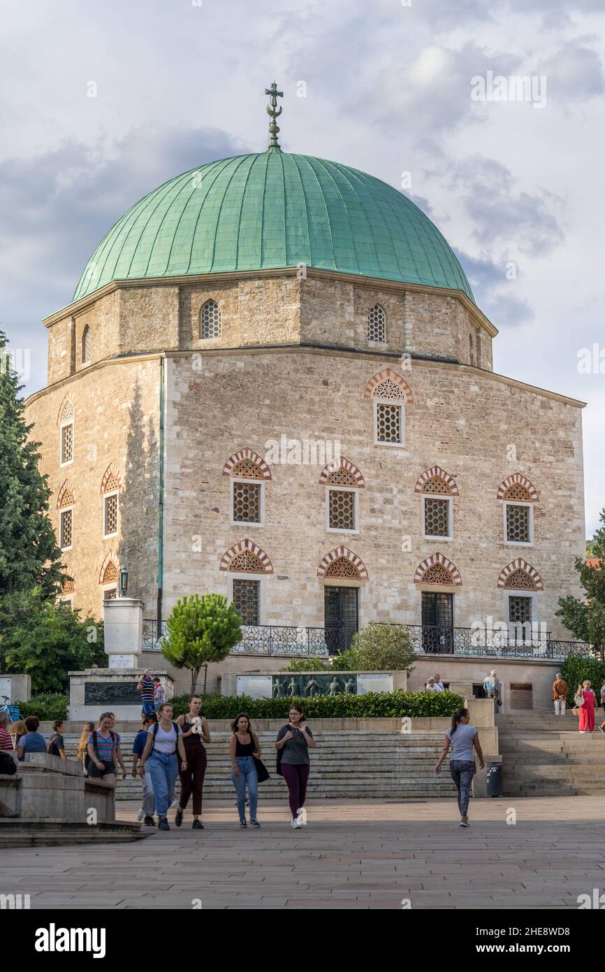 Students pass by the Mosque of Pasha Qasim that now serves as a Catolic church in the trendy university town of Pecs in Southern Hungary Stock Photo