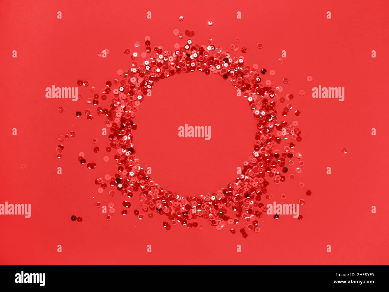 Sequins red confetti lined in round frame red background. Abstract festive composition place for text Stock Photo