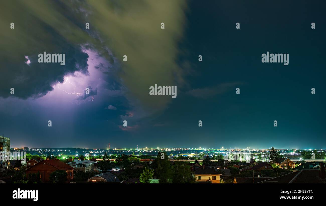 Thunderstorm over the city at night, bright lightning among dense clouds Stock Photo