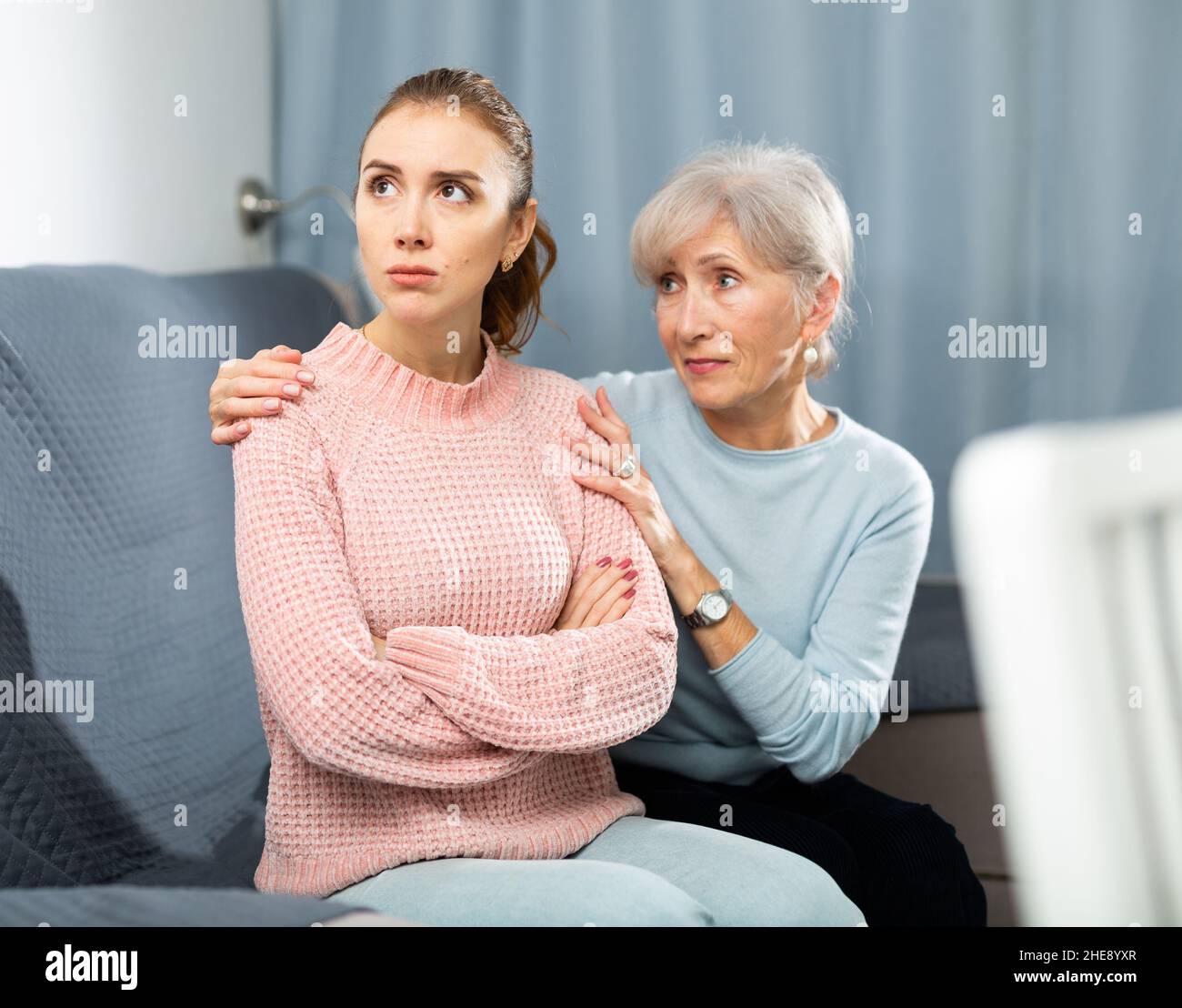 Senior woman calming chagrined adult daughter in home living room Stock ...