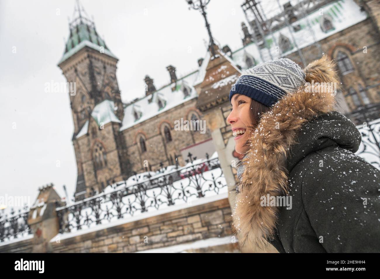 Ottawa winter city Asian woman walking by Canadian Parliament in Ontario, Canada. Travel tourist visiting popular attraction during snowfall wearing Stock Photo