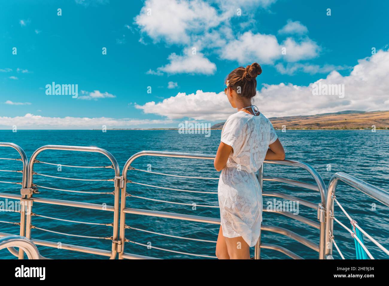 Cruise ship elegant lady in white cover up beach dress relaxing on boat deck watching scenery landscape on Mediterranean sea, Europe summer travel Stock Photo