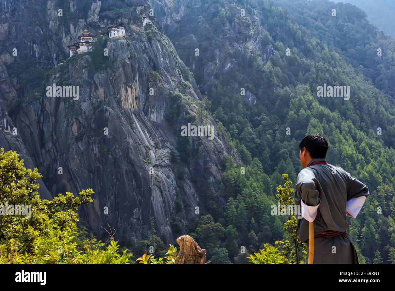 Bhutanese man watching Paro Taktsang (also known as Tiger's Nest) perched on the cliff, Paro, Bhutan Stock Photo