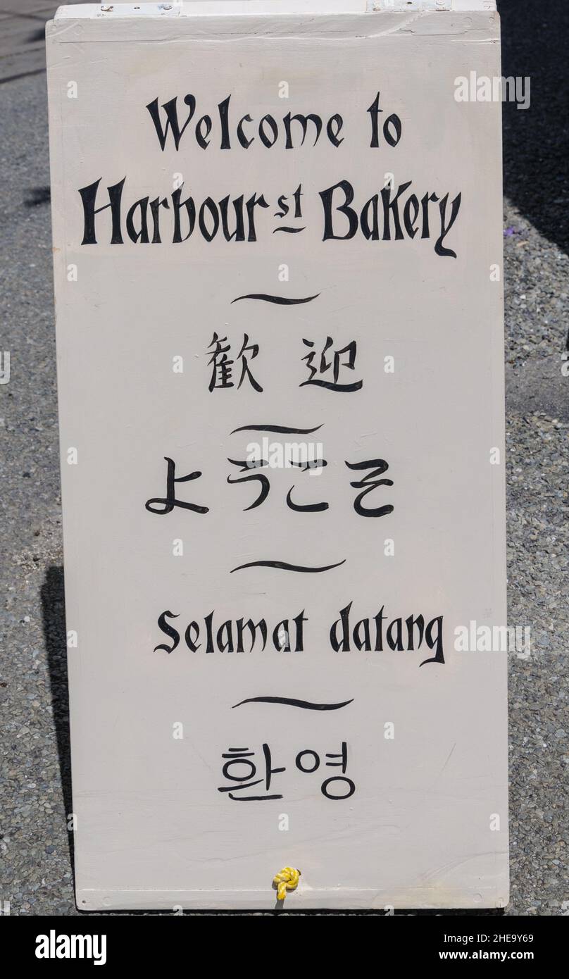 Welcome sign in multiple languages to the Oamaru Harbour Bakery Stock Photo