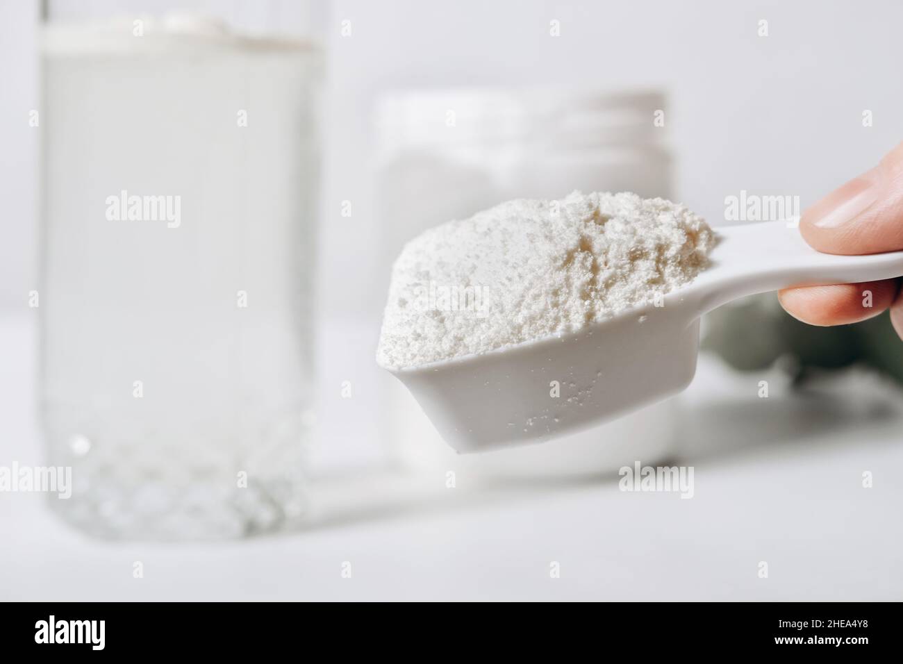 hand holding scoop of fish collagen. collagen peptides in container or jar. powder for mixing drink. Healthcare supplement concept. collagen for skin Stock Photo