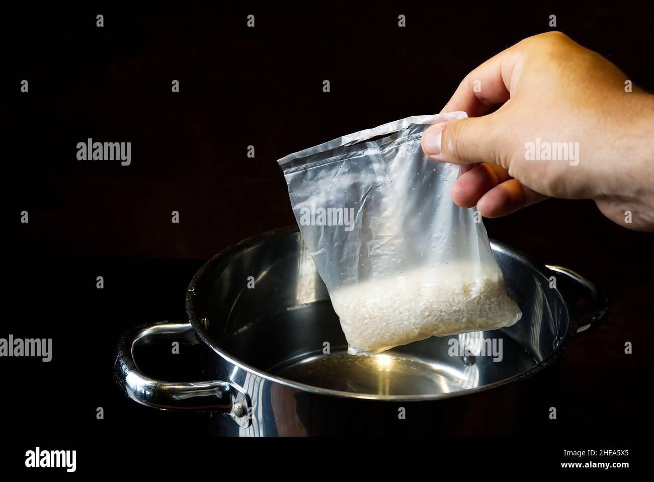 Boiling rice in portion bag. A bag of white, cooked rice is held with a ...