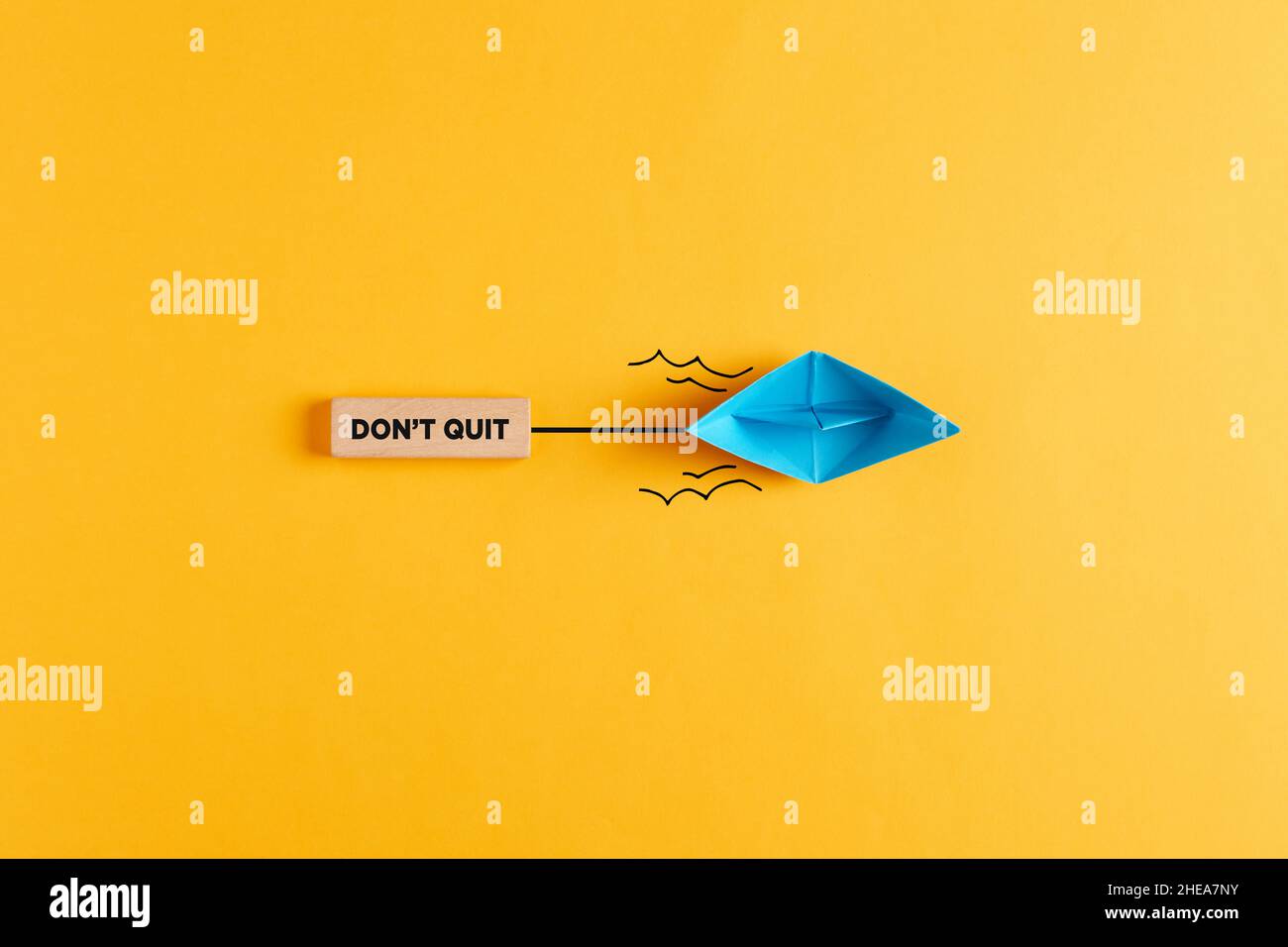 Paper boat pulls a wooden banner with the message don't quit. Persistence or determination in business or education motivational message. Stock Photo