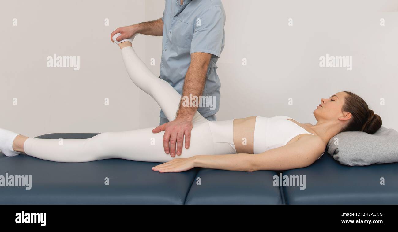 Knee pain relief in clinic. Doctor physiotherapist doing healing treatment on patient leg. Therapist giving leg and calf massage. Osteopathy Stock Photo