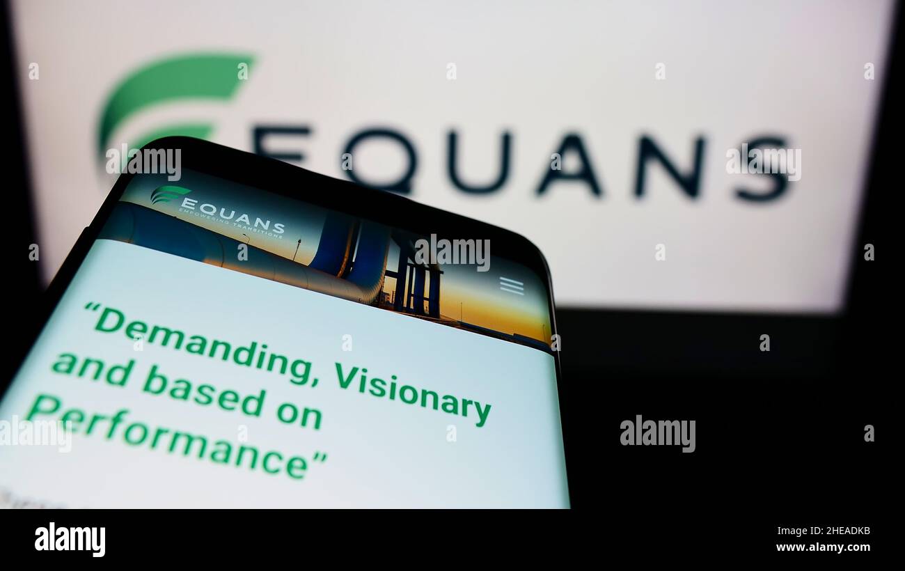 Smartphone with webpage of French facility management company EQUANS on screen in front of business logo. Focus on top-left of phone display. Stock Photo