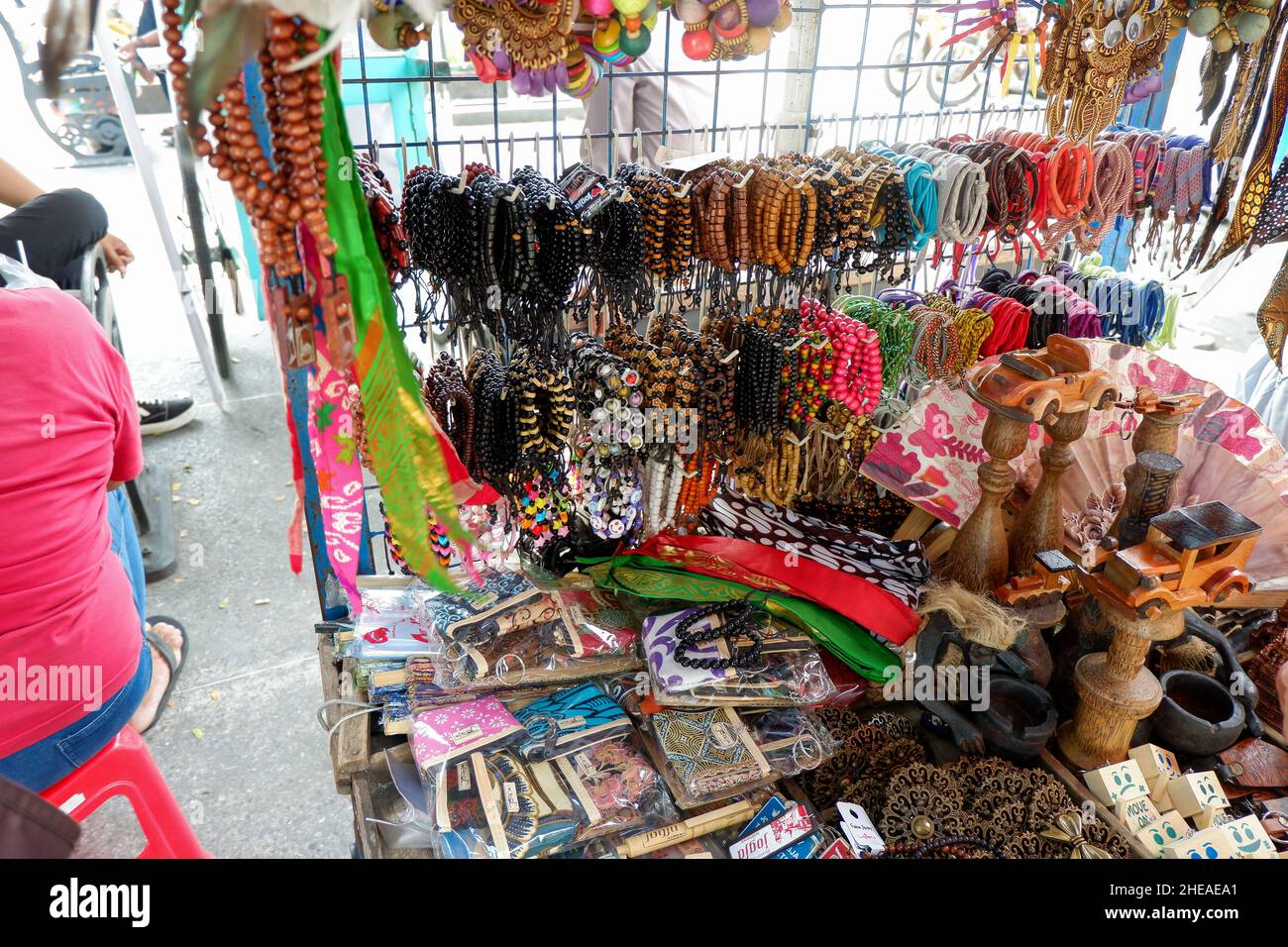 stall selling accessories on the sidewalk on Jalan Malioboro.  there are bracelets, bandanas, hair ties, prayer beads for worship and toy cars made of Stock Photo