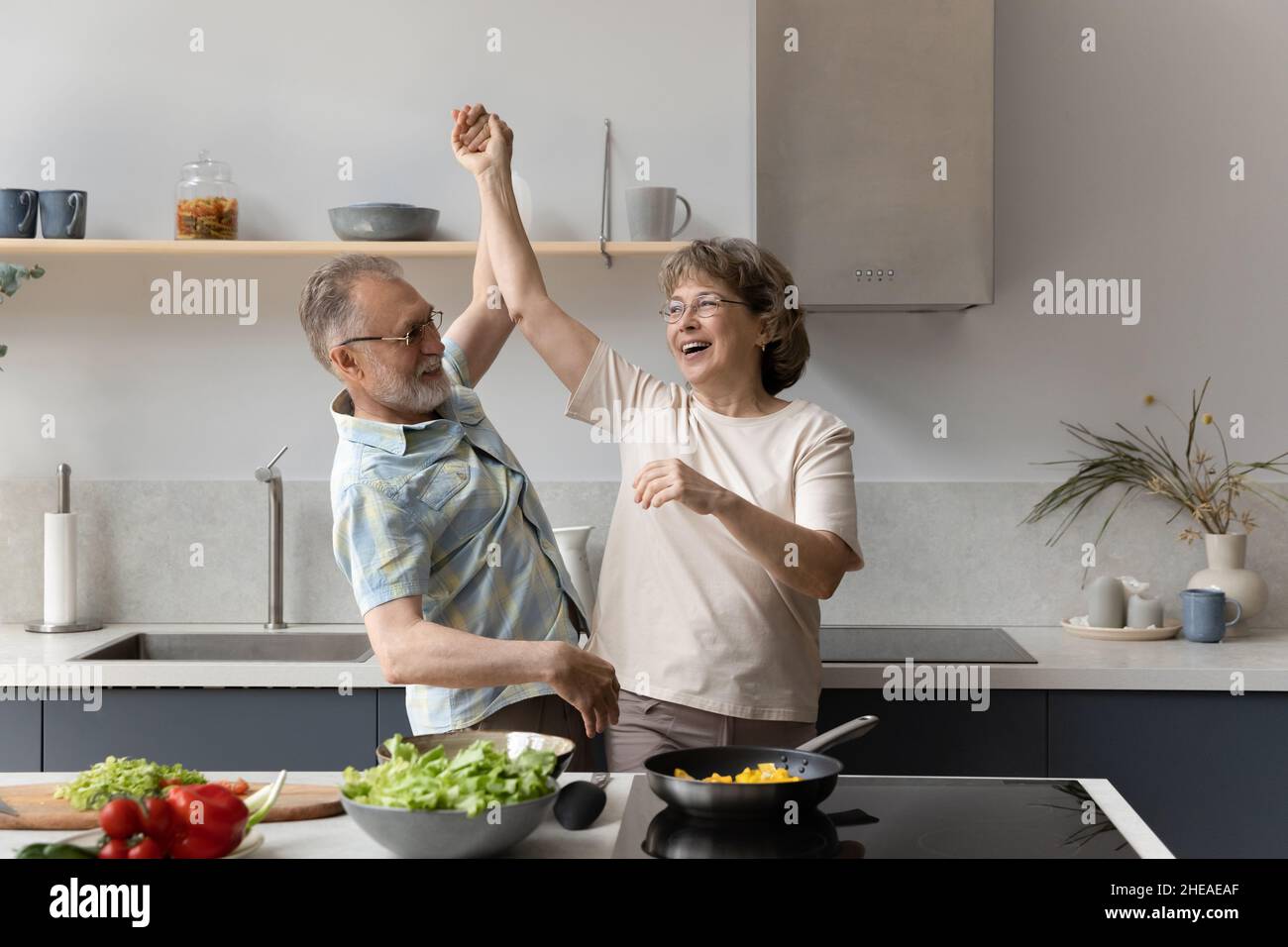 Happy middle aged man dancing with laughing elderly senior wife. Stock Photo
