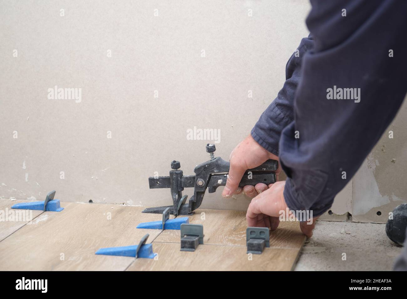Mason hands adjusting tile levelers between ceramic wood effect tiles Stock Photo Alamy