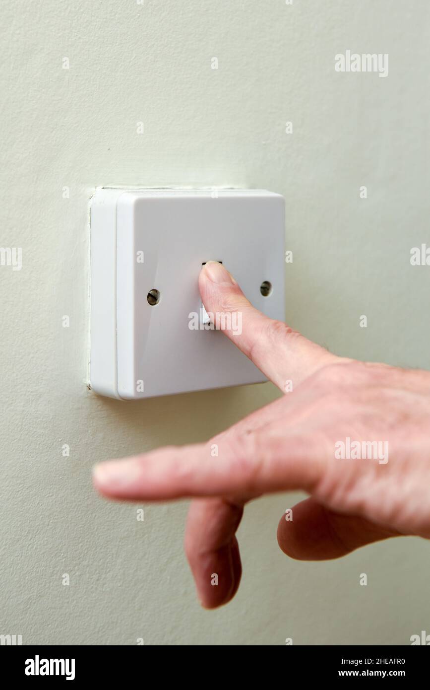 Person turning off light switch to save on energy bills and waste of electricity Stock Photo Alamy