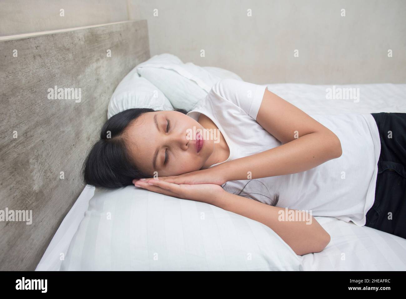 Young asianwoman sleeping tired dreaming. Women pretending to sleep and making gesture. Sleepy tired woman falling asleep being exhausted. Stock Photo