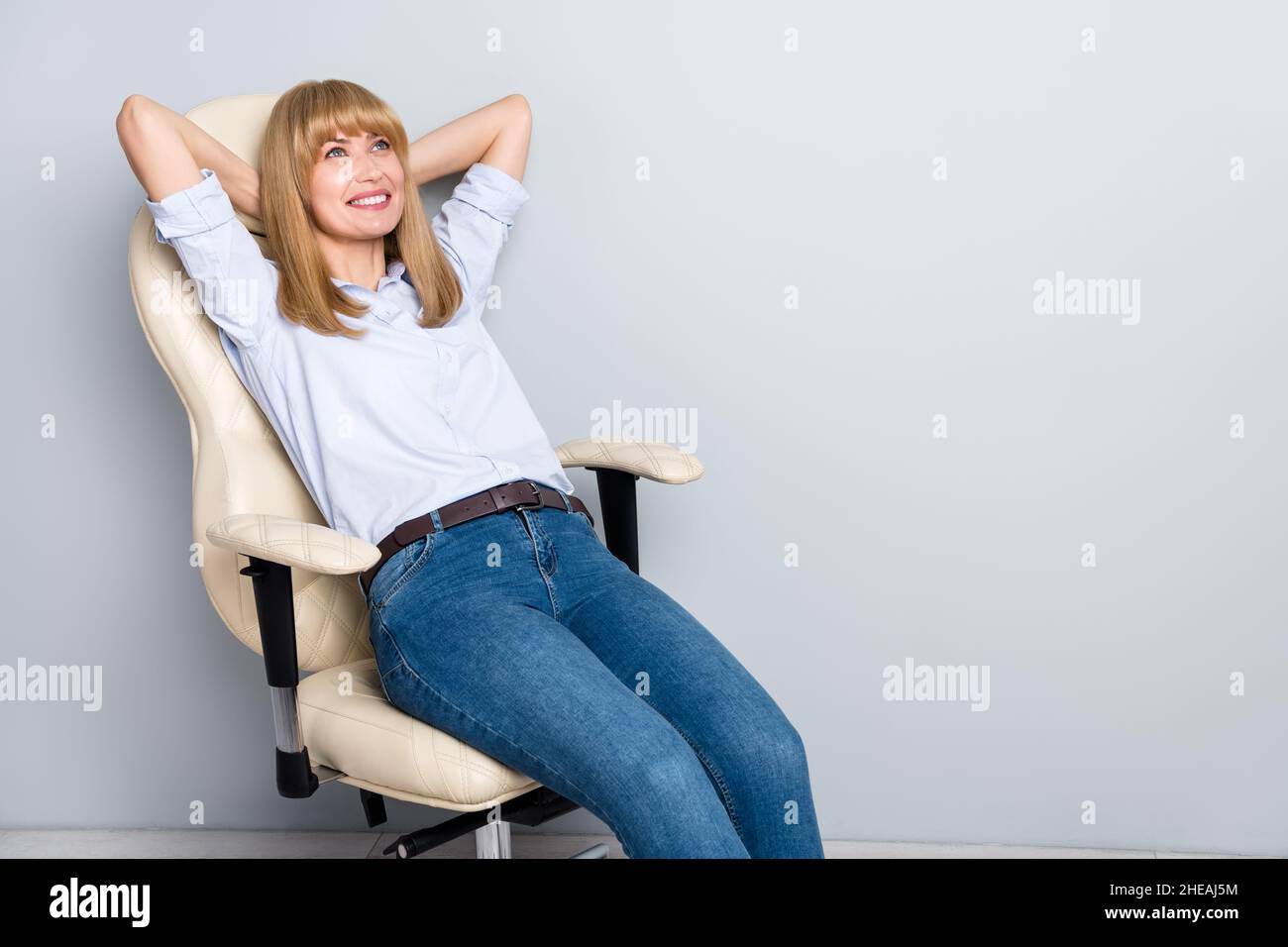 Photo of candid marketer lady sit armchair hands head dreaming rest wear denim  jeans isolated over grey color background Stock Photo - Alamy