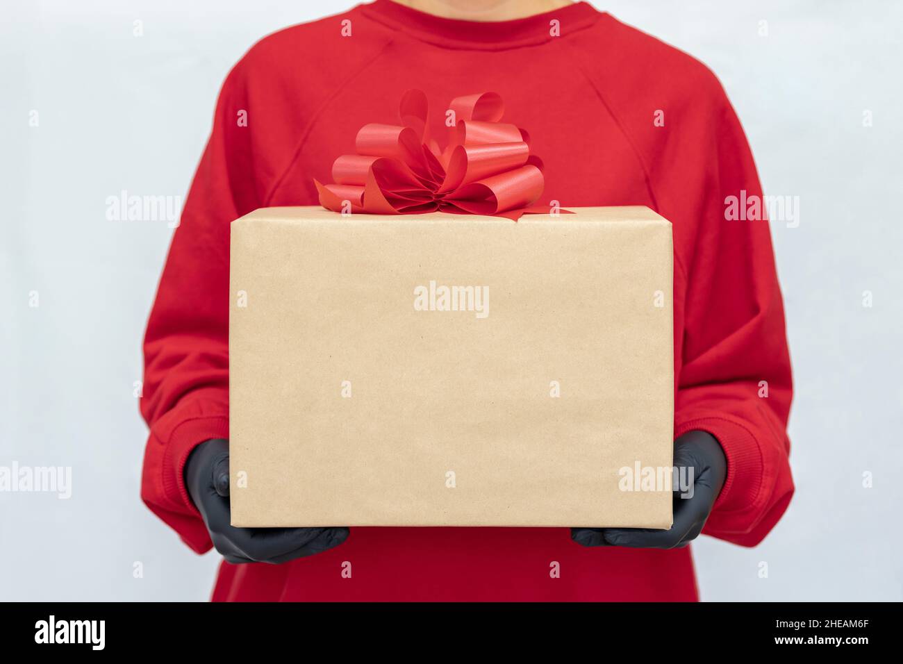 Express delivery. A young woman holds a cardboard boxes with a red bow