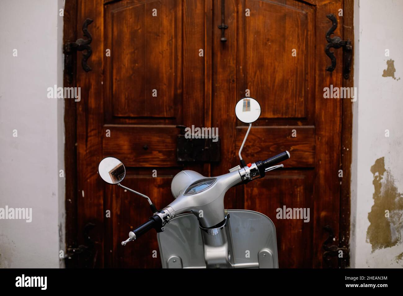 Shallow depth of field (selective focus) details with a scooter with a wooden door in the background. Stock Photo