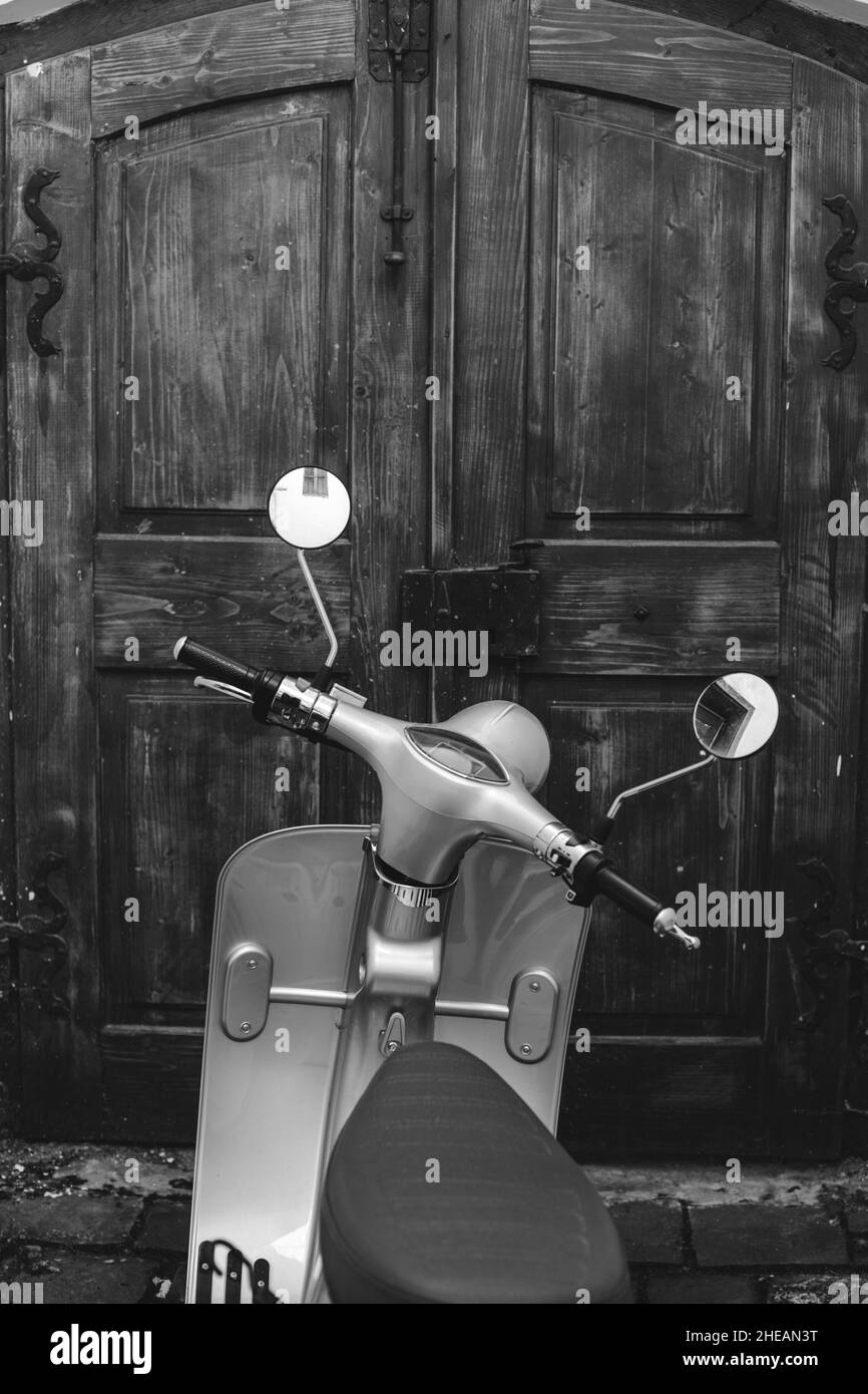 Shallow depth of field (selective focus) details with a scooter with a wooden door in the background. Stock Photo
