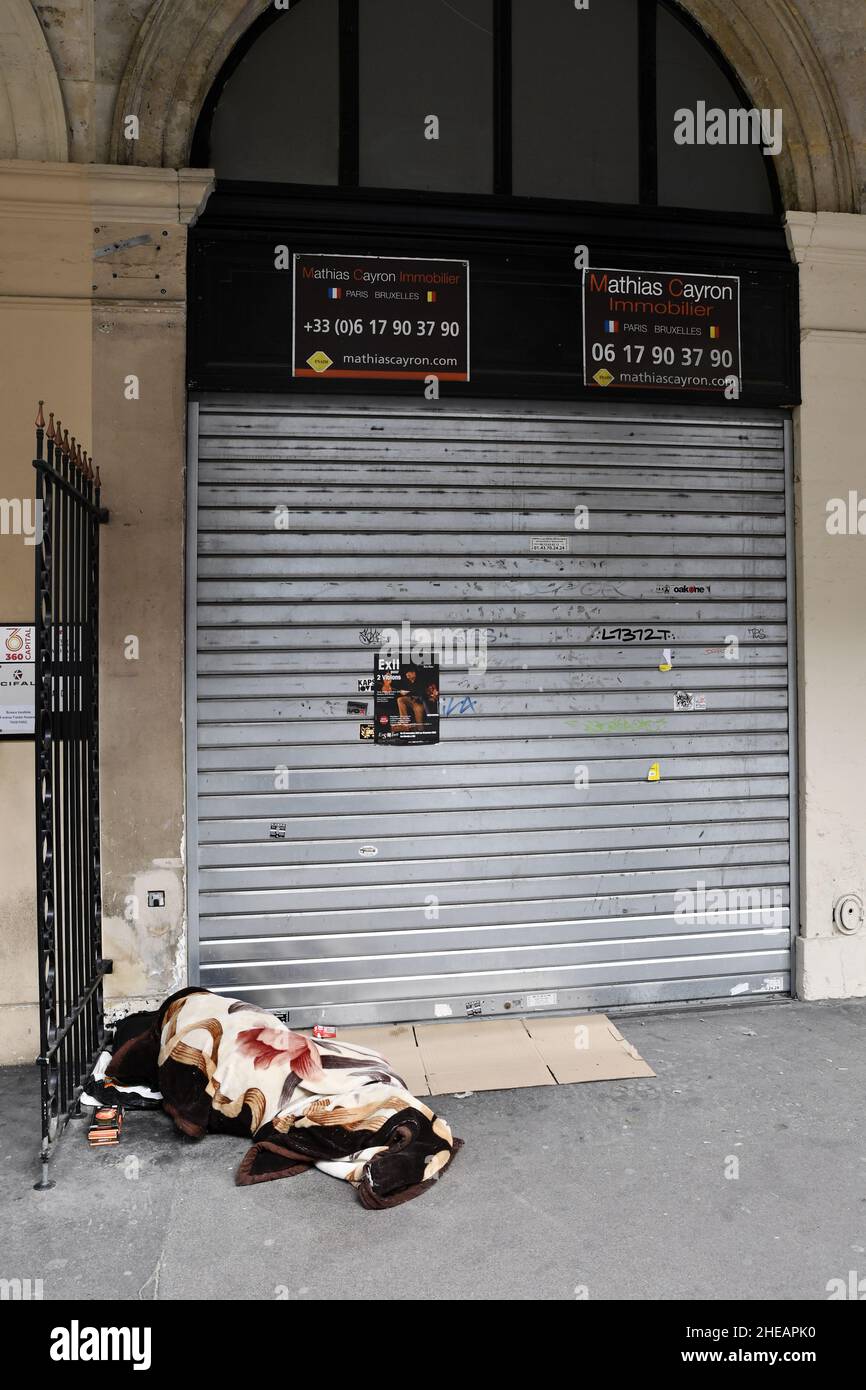 Homeless sleeping in front of a closed store by COVID Crisis and traffic difficulties of circulation - Rue de Rivoli - Paris - France Stock Photo