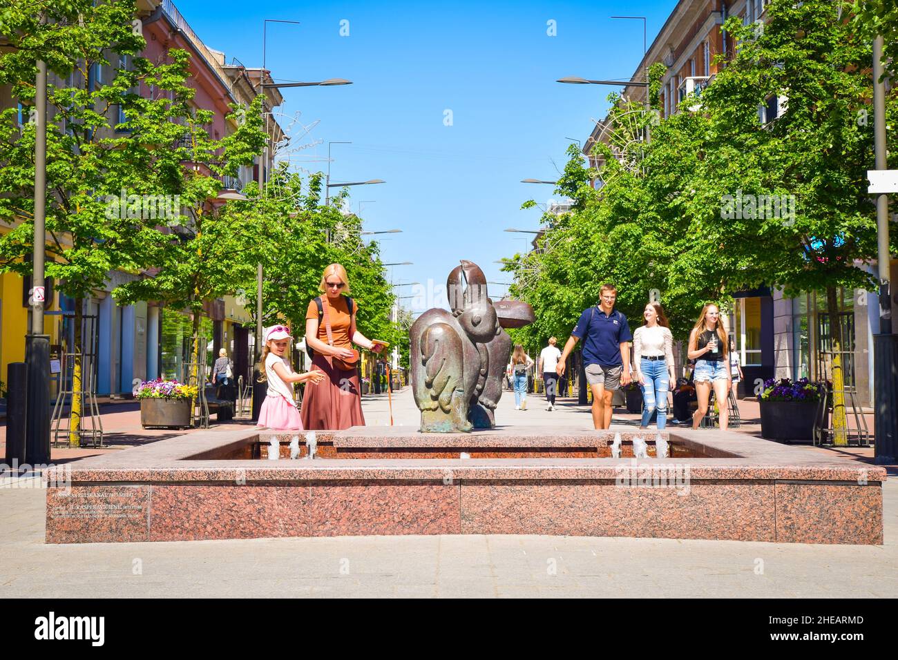 Siauliai main boulevard street with fountain. Lithuanian people enjoy summer day in Siauliai city center in hot day refreshing water. Stock Photo