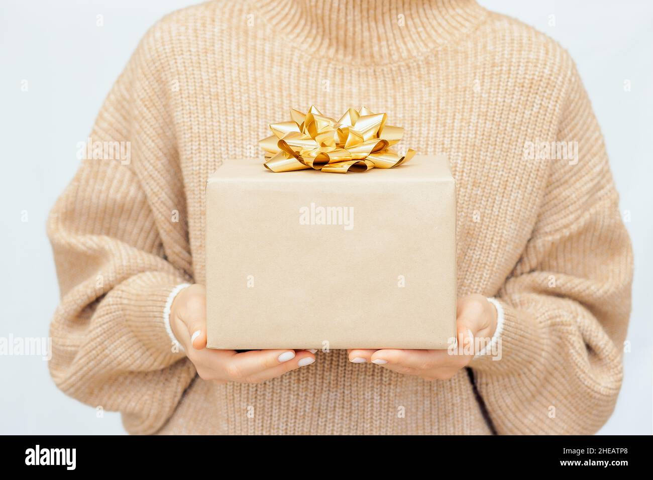 Woman's hands gift box with cold ribbon. woman in warm beige jumper Hold present box with bow.  Stock Photo