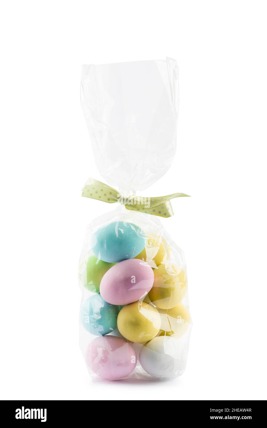 Small colorful easter eggs in transparent bag on white background Stock Photo