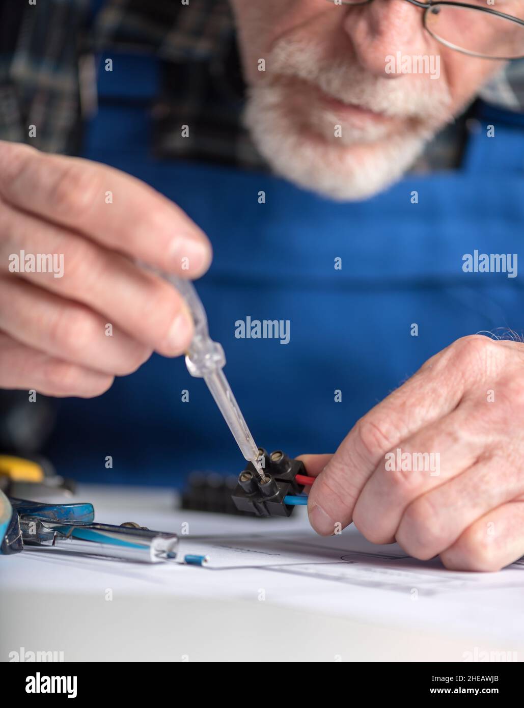 Senior electrician connecting wires in terminal block Stock Photo