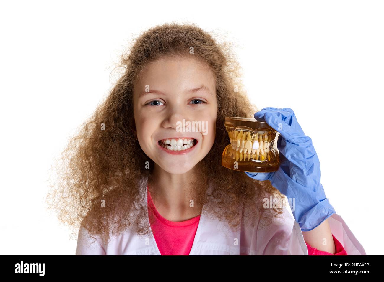 Half-length portrait of cute beautiful little girl, child in image of dentist doctor wearing white lab coat and gloves isolated on white studio Stock Photo