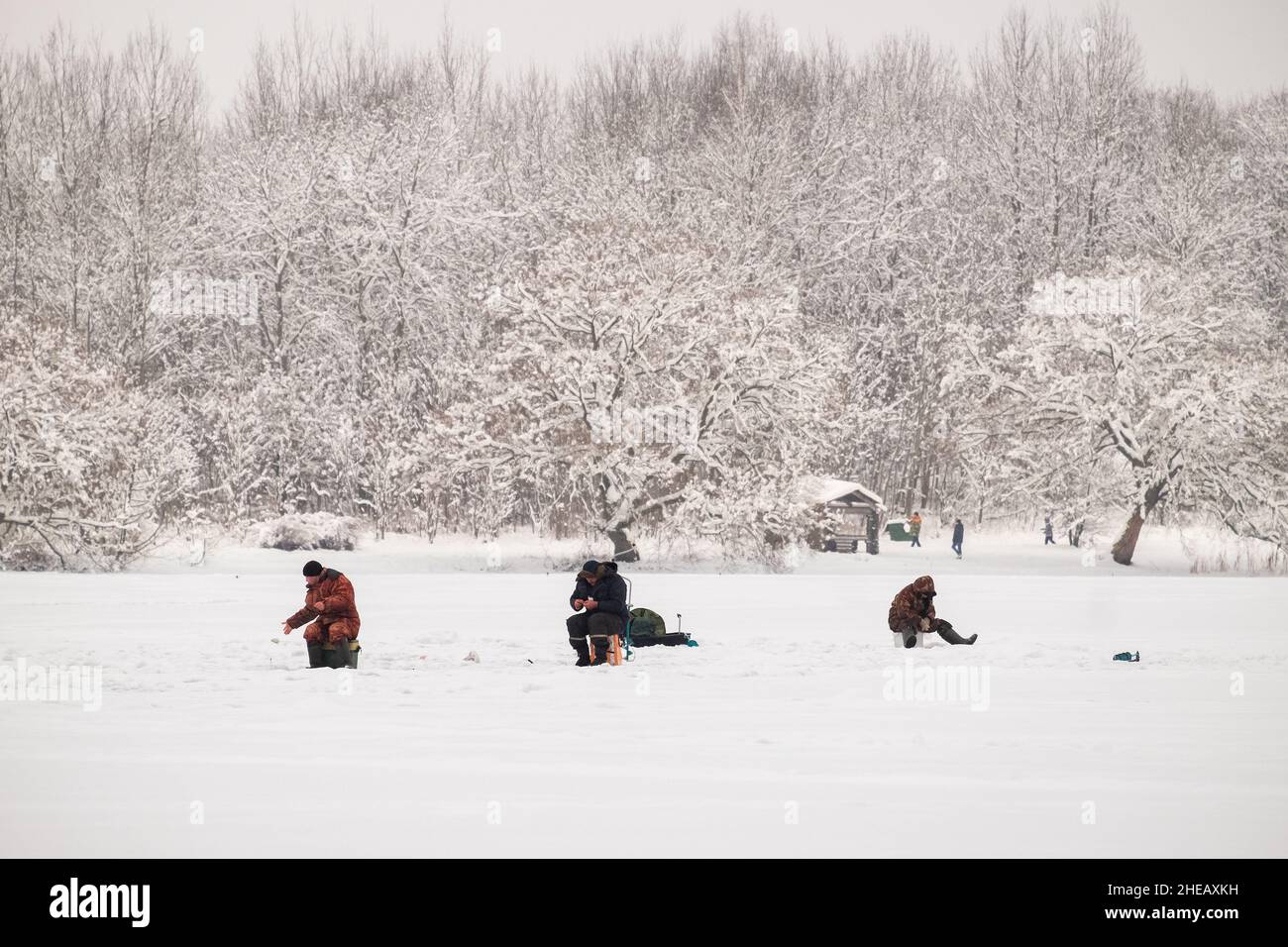 Ice fishing. Winter fishing from ice on the lake (reservoir) on a cold day. warmly dressed fishermen Stock Photo
