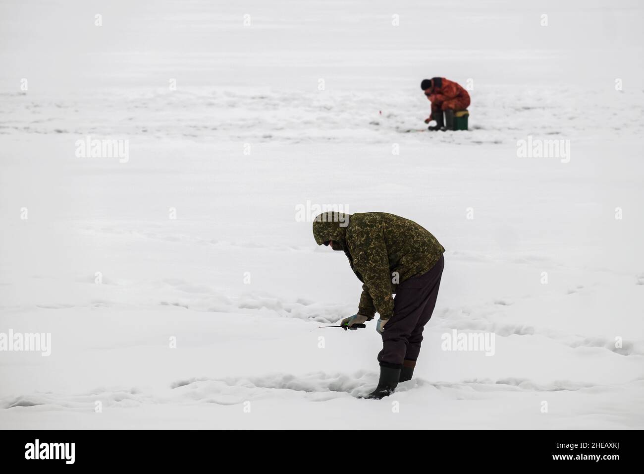 Ice fishing. Winter fishing from ice on the lake (reservoir) on a cold day. warmly dressed fishermen Stock Photo