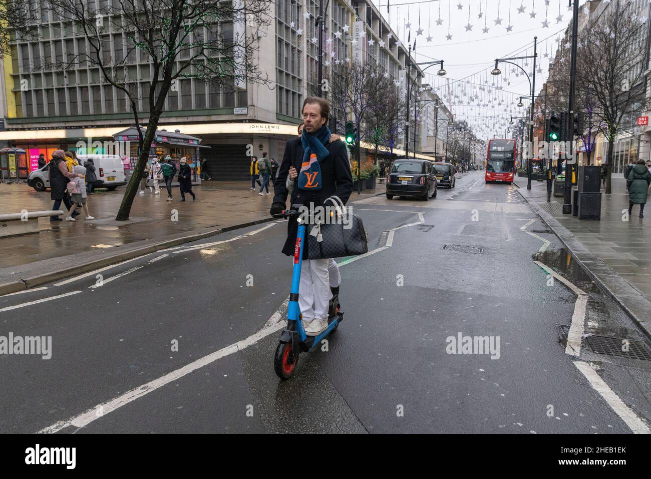 Shoppers travelling on e-scooter along Oxford Street during the January Sales, London, England, United Kingdom Stock Photo