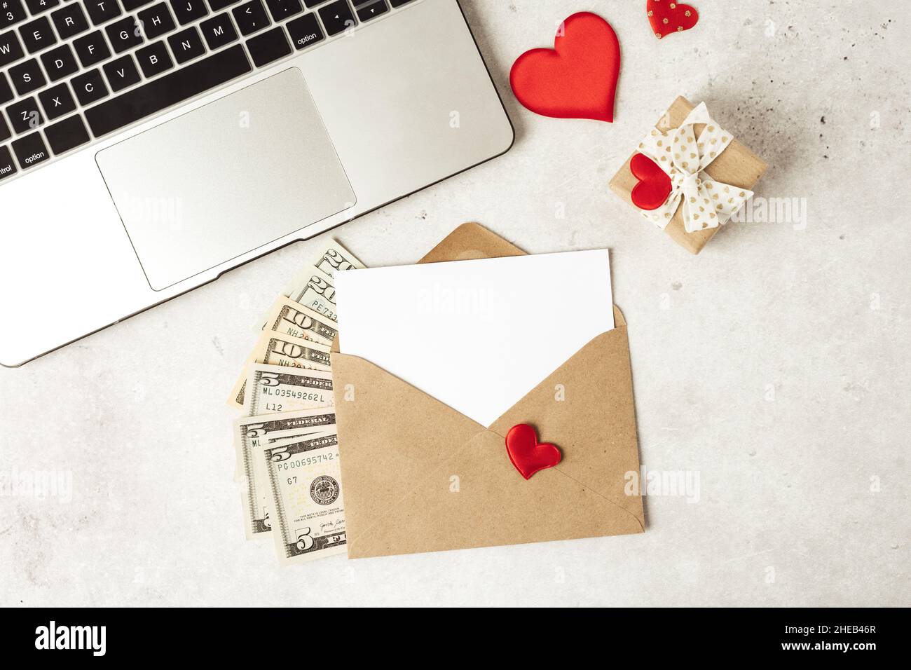 Red paper envelope with blank paper white note mockup. Flat lay of gray working table background with Valentine gift, letter, heart shape, laptop and Stock Photo
