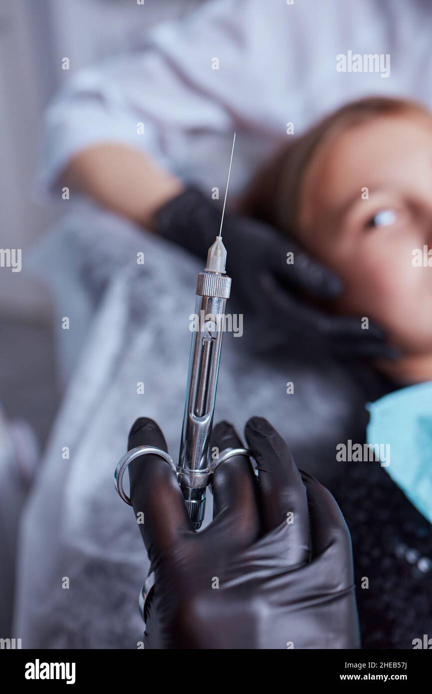 Little girl at dentist office, getting local anesthesia injection into