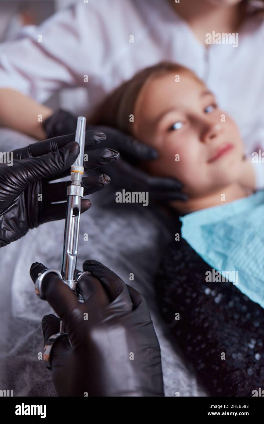 Little girl at dentist office, getting local anesthesia injection into