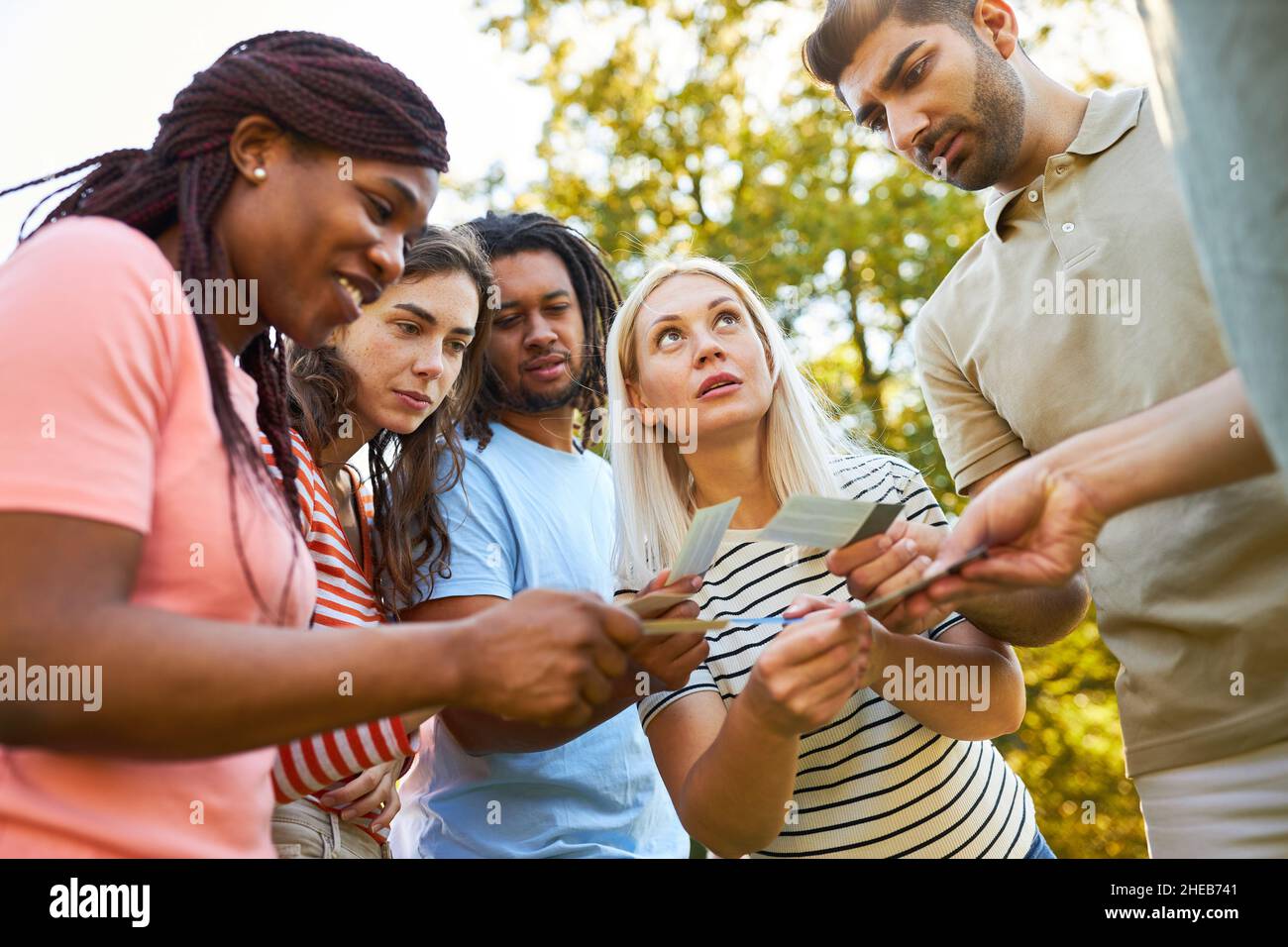 Young people in team building workshop solve a task together outdoors in summer Stock Photo