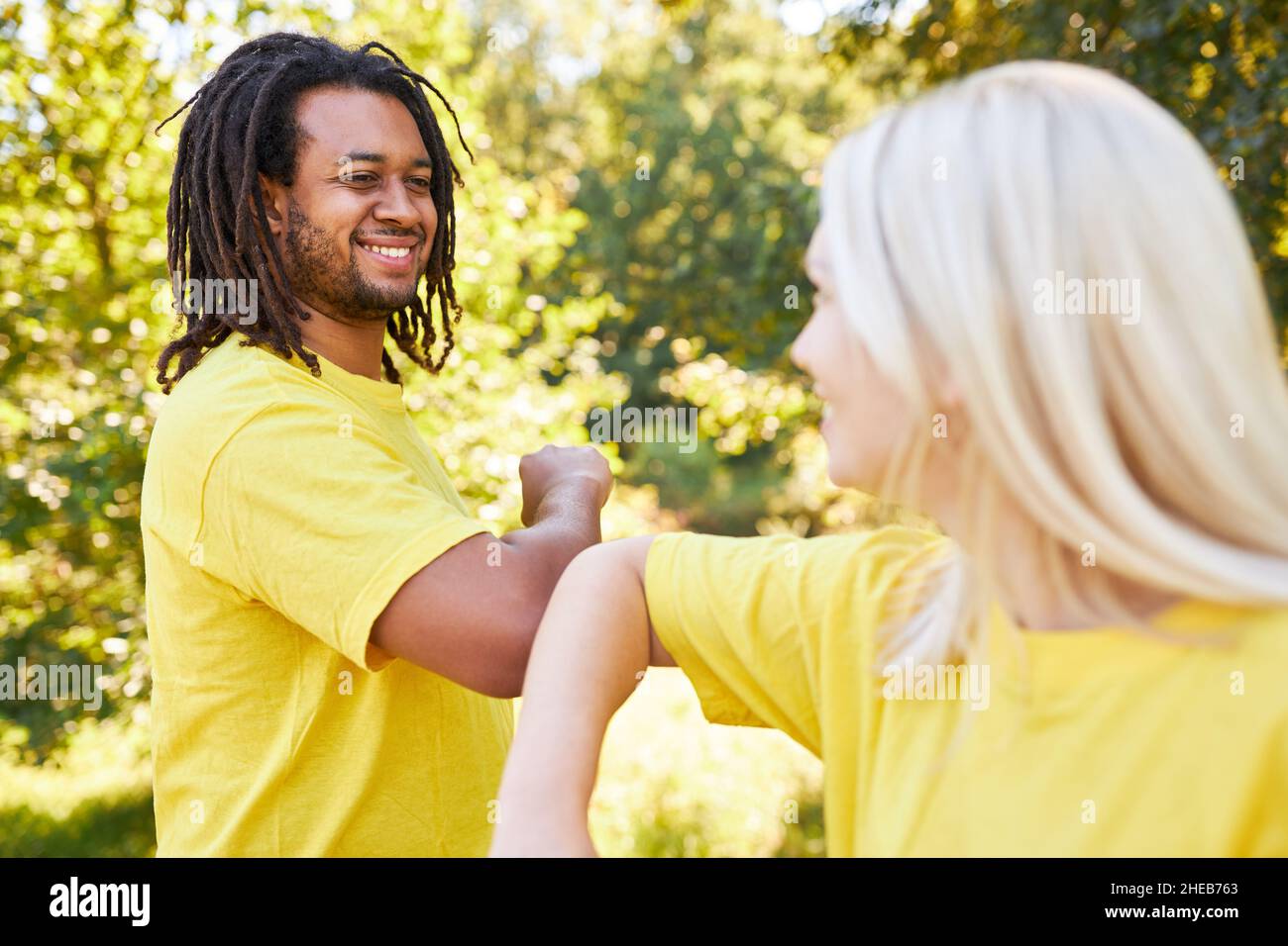 Young man and young woman at elbows greeting for distance and safety in summer Stock Photo