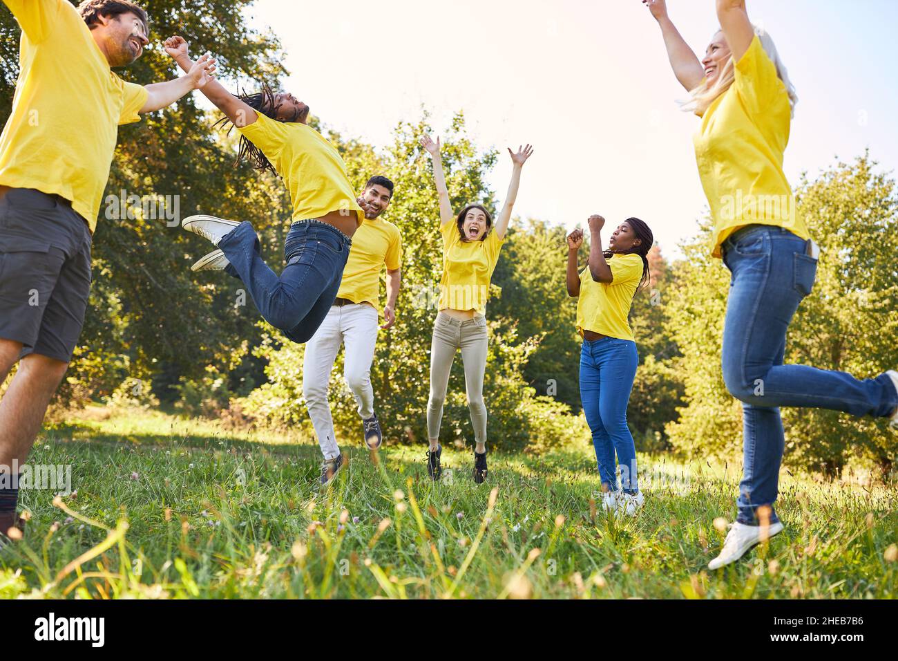Group of young people jumping in a meadow as an exercise for team