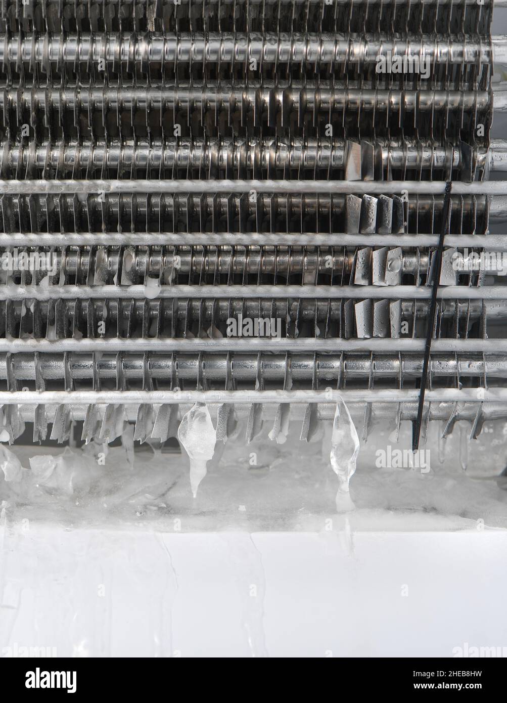 The drainage plug on a non-frost freezer is blocked with ice, having to remove protective backing to unblock by melting with an hairdryer. Stock Photo