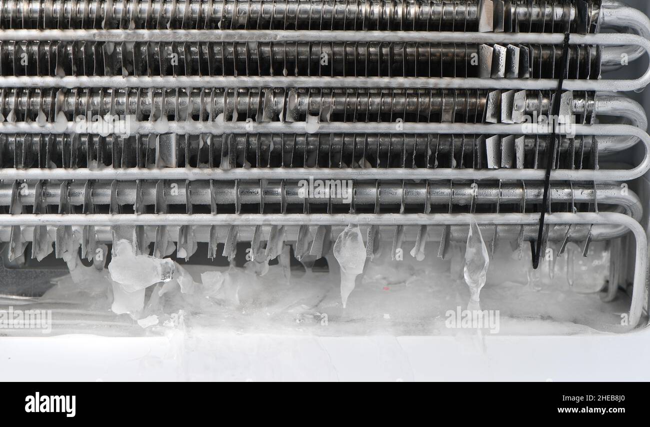 The drainage plug on a non-frost freezer is blocked with ice, having to remove protective backing to unblock by melting with an hairdryer. Stock Photo