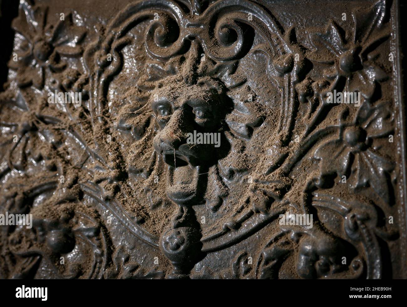An ornamental decorative  lions head with piecing eyes on a antique cast iron  fireplace found in an old home before renovation work begins. Stock Photo