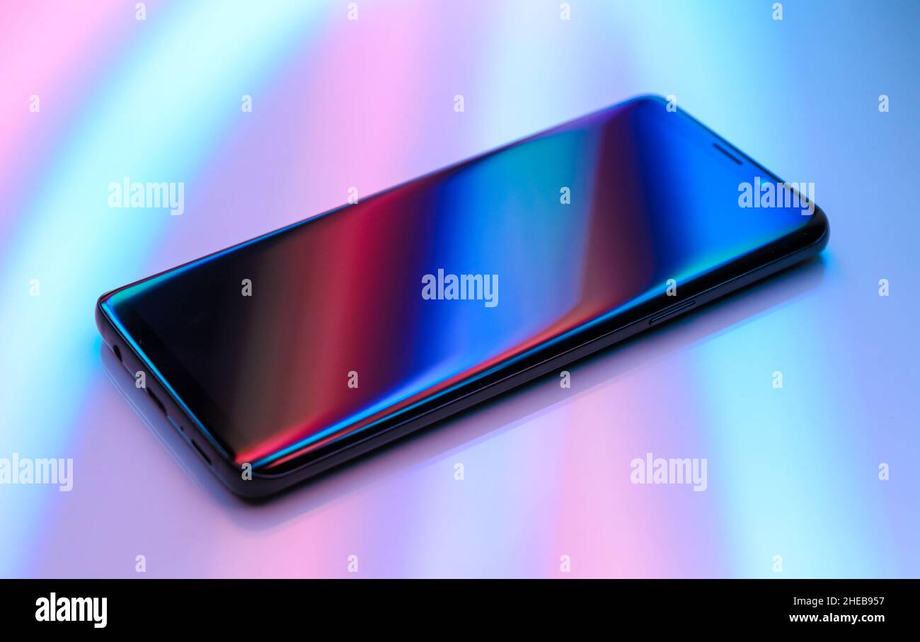 Smartphone on white background with colorful reflections and blue and red lighting effects Stock Photo