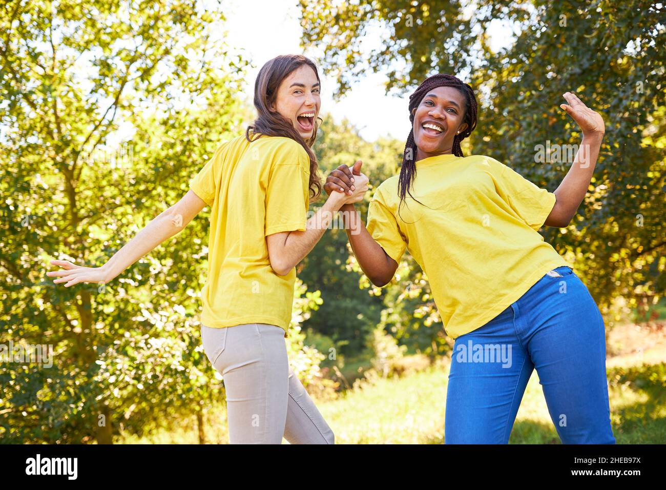 Two young women laugh and dance together at a team building workshop Stock Photo